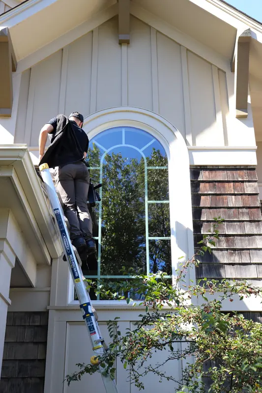 Technician on a ladder cleaning an arched window