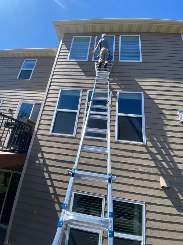 Ladder set against a tall sided home for second-story window cleaning