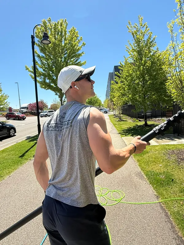 Technician with a water-fed pole on the sidewalk beside a mid-rise
