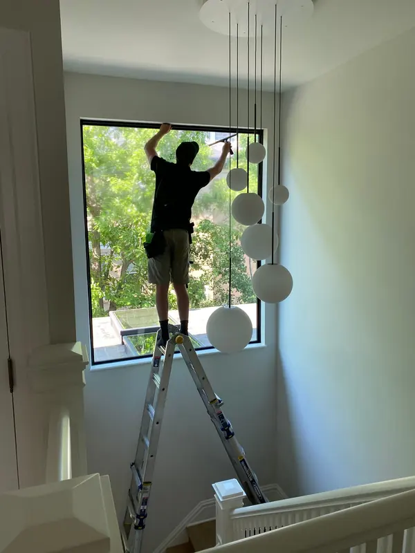 Cleaning a tall interior stairwell window from a ladder