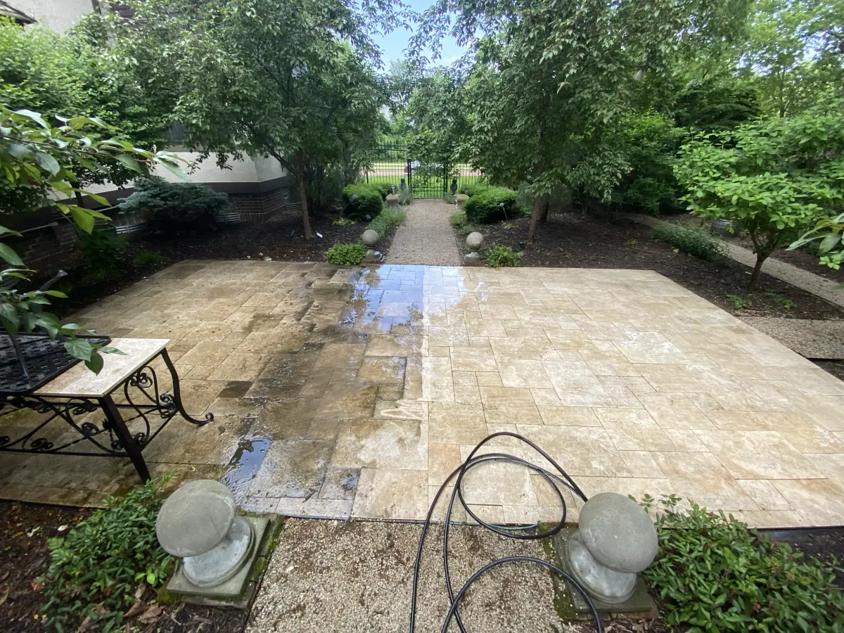A stone patio half pressure washed